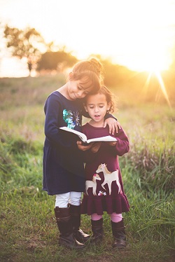girls reading a book in the sun