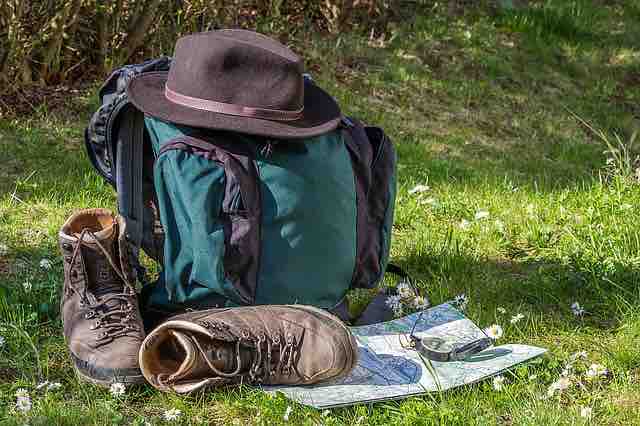 rucksack with hat, hiking boots and map and compass in a field with flowers